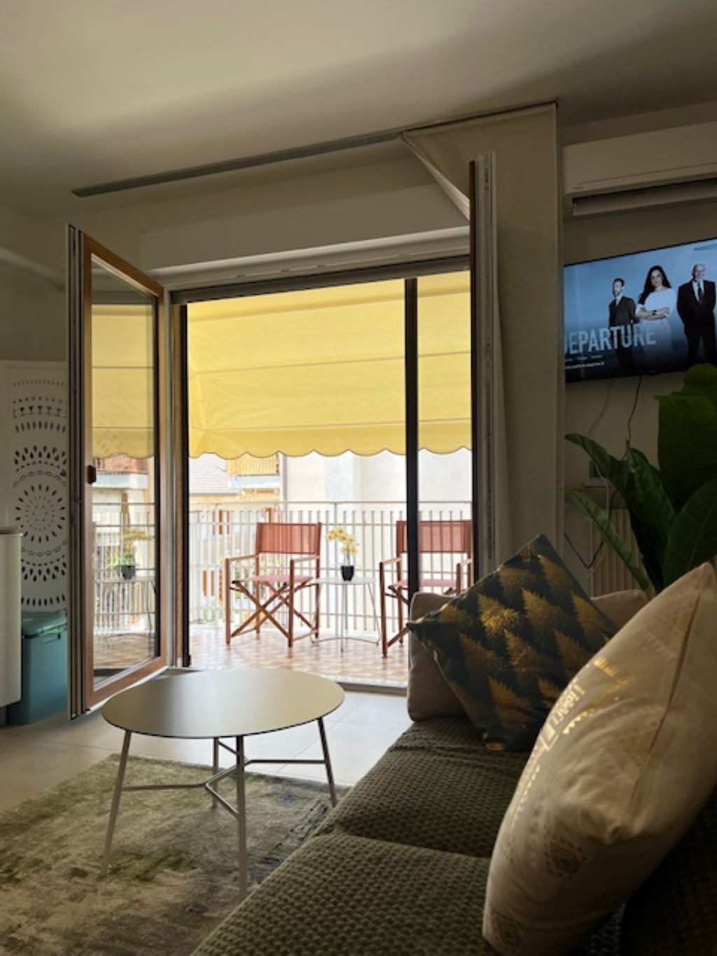 Un salon avec un canapé, une petite table et un téléviseur fixé au mur.