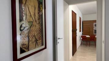 Un pasillo con una obra enmarcada en la pared, que conduce a un comedor con sillas y una mesa.