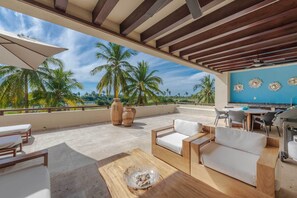 A rooftop patio with outdoor furniture, a dining area, and decorative wall art. - Luxury Punta Mita Golf Condo – Family Getaway, Private Pools & Beach Clubs (Nayarit)