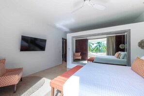 A bedroom with a bed, a television, and a view through a glass door. - Luxury Punta Mita Golf Condo – Family Getaway, Private Pools & Beach Clubs (Nayarit)
