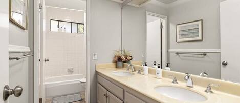 Une salle de bain moderne avec deux lavabos, un grand miroir et une baignoire.