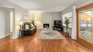 Ein Wohnzimmer mit Kamin, Ledersofa, Fernseher und einem großen Fenster.