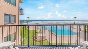 Un balcon avec vue sur une piscine et l’océan.