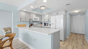 Une cuisine moderne avec des meubles blancs, un îlot central et un four à micro-ondes.