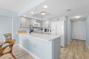 A modern kitchen with white cabinets, a central island, and a microwave.