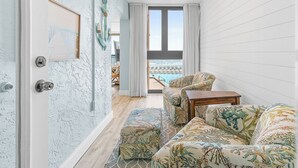 Une chambre avec vue sur une piscine, une porte ornée d’un mur à motifs et des meubles à motifs.