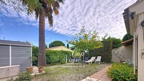A backyard with a stone pathway, a palm tree, and a hedge. - 3-star-rated cottage for 6 people in a residence with a 50-meter pool near Pramousquier Beach (Le Lavandou)
