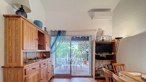 A compact kitchen with wooden cabinets, a dining table, and a TV. - 3-star-rated cottage for 6 people in a residence with a 50-meter pool near Pramousquier Beach (Le Lavandou)