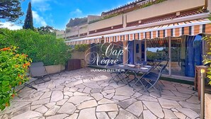 Une terrasse avec un sol en pierre, du mobilier d’extérieur et un auvent à rayures.