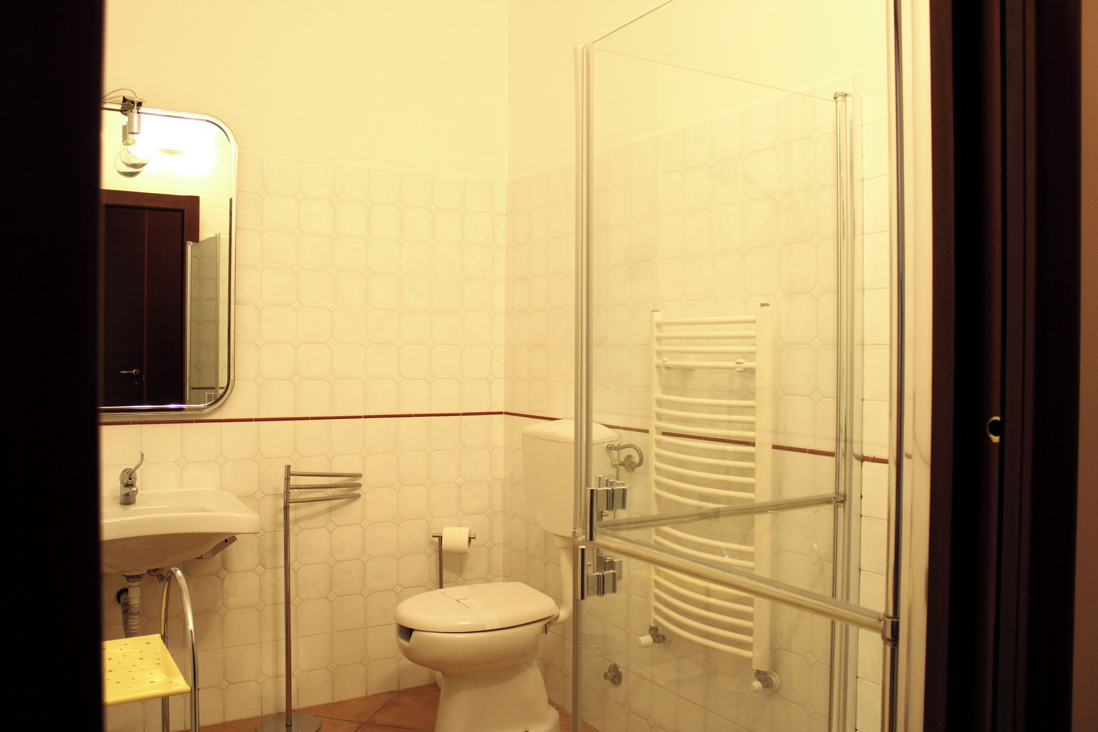 Bagno con WC, lavandino e cabina doccia in vetro.