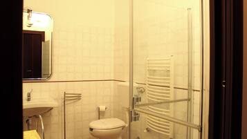 Bagno con WC, lavandino e cabina doccia in vetro.