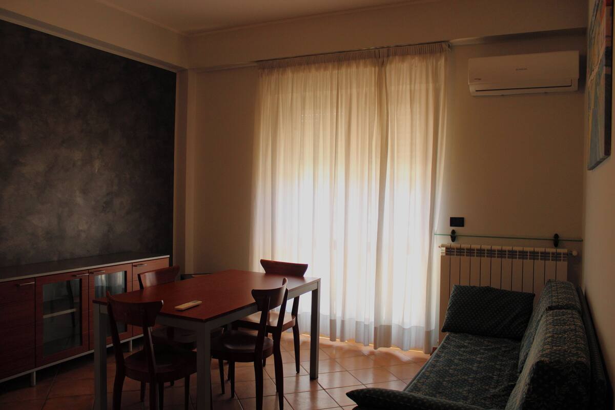 A compact living space with a dining area, a sofa, and a kitchenette.
