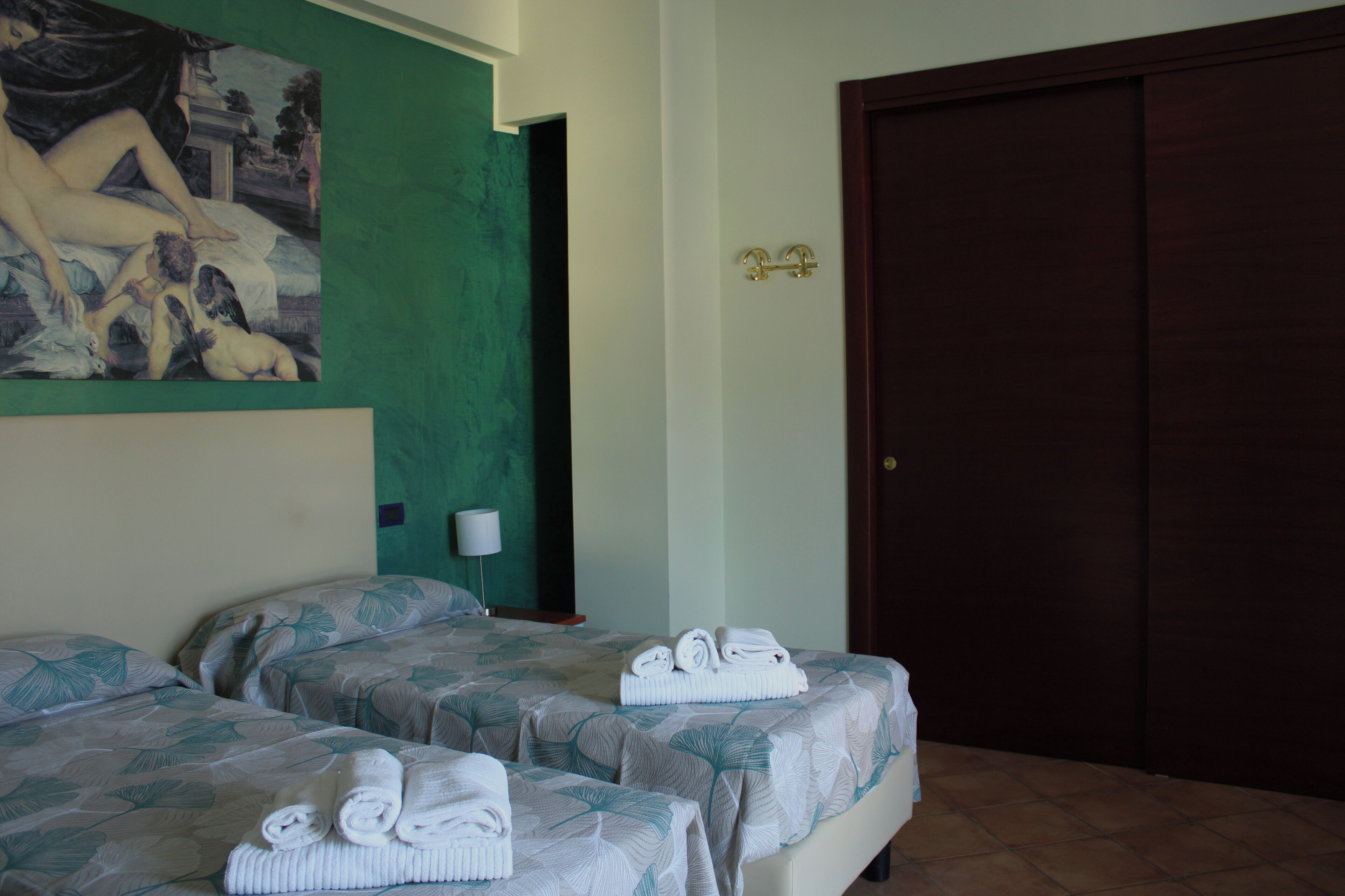 Een hotelkamer met twee bedden, een schilderij aan de muur, een deur en handdoeken op de bedden.