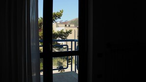 Vista da un balcone con ringhiera in metallo, cielo sereno e edifici sullo sfondo.