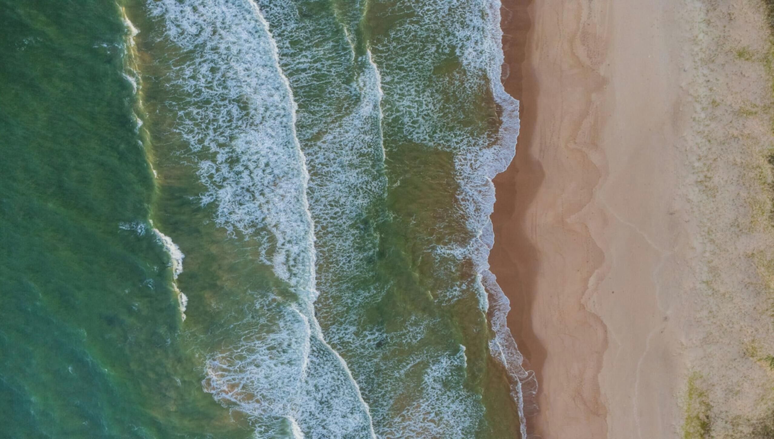 Vista aérea de una playa con olas acercándose a la orilla.