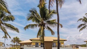 A resort with multiple-story buildings, palm trees, and a clear sky. - Baixio Residences by ¼ UmQuarto. (Baixio)