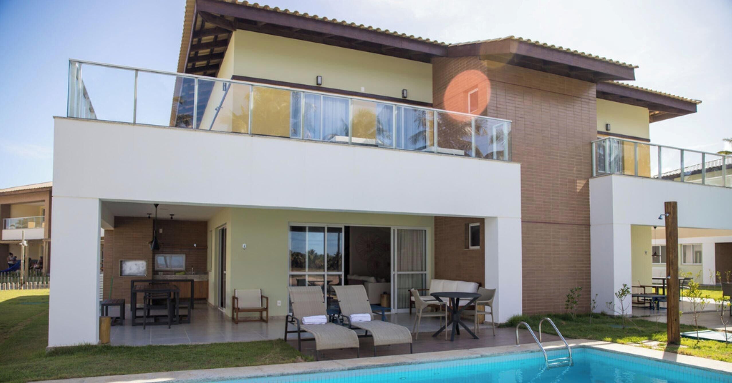 A two-story residential building with a swimming pool, outdoor seating, and a balcony.