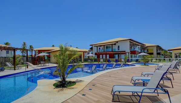 A resort with a swimming pool, lounge chairs, and multiple buildings with balconies.