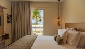 Een hotelkamer met een bed, een nachtkastje, een lamp en uitzicht op palmbomen door het raam.