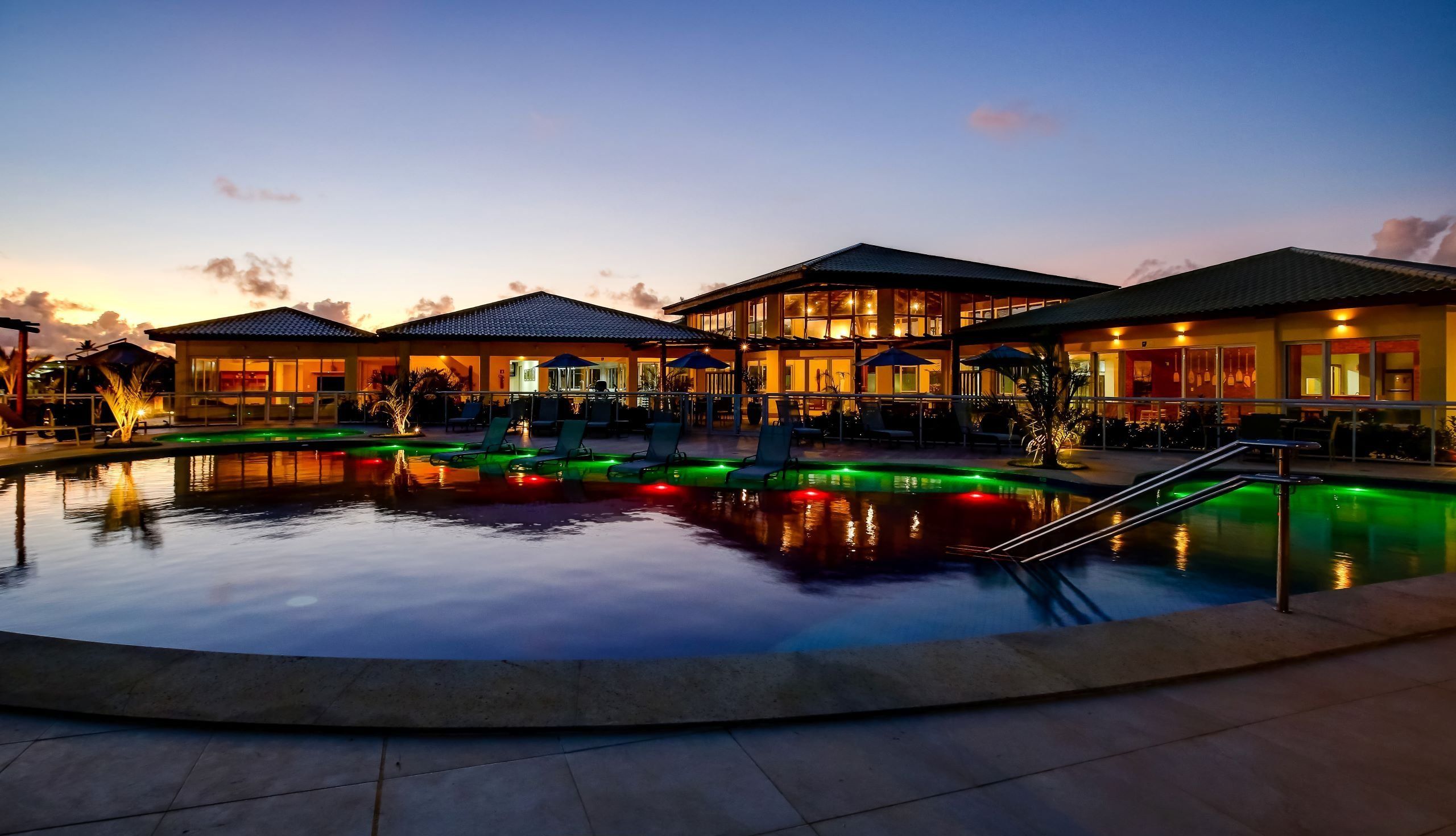 Ein Hotel mit Schwimmbad, Außenbereich und einem Sonnenuntergangshimmel.