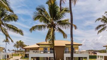 Un resort con edificios de varios pisos, palmeras y un cielo despejado.