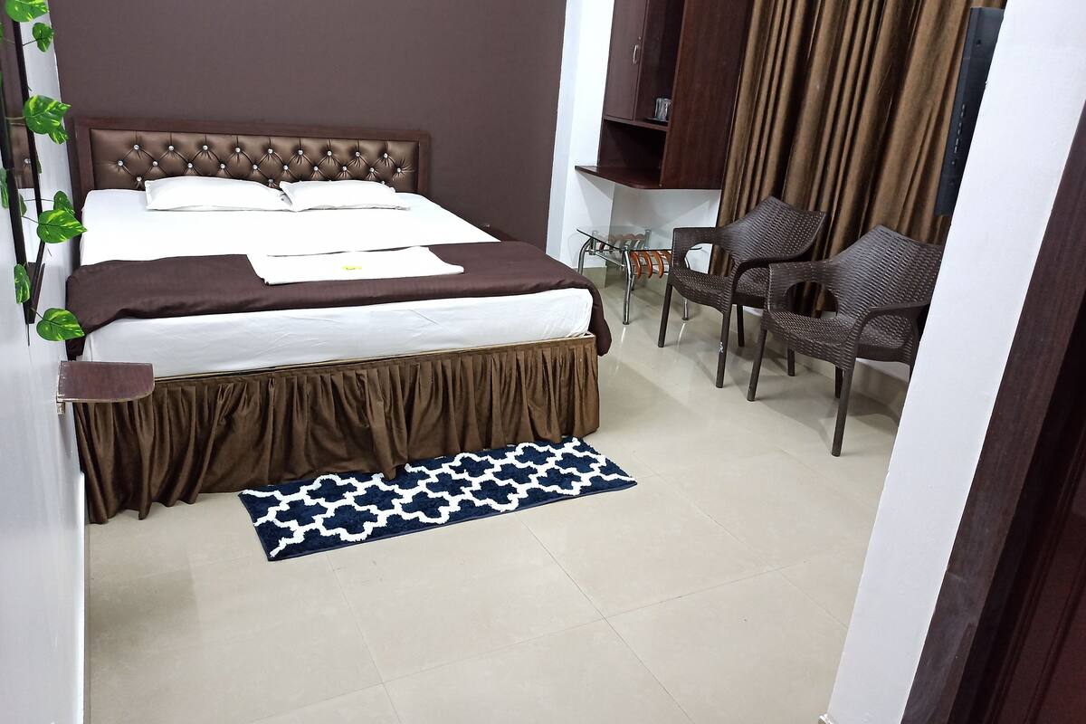 A bedroom with a bed, a wooden cabinet, a chair, and a small table.