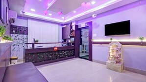 Eine moderne Hotelhalle mit einer Rezeption, einem an der Wand befestigten Flachbildfernseher und einer dekorativen Pflanzengestaltung.