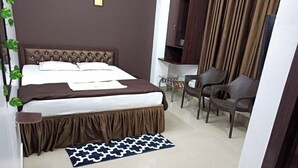 Ein Hotelzimmer mit einem großen Bett, einem Sessel, einem Schreibtisch und einem Kleiderschrank.