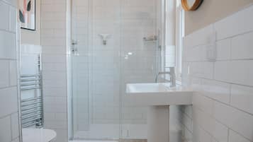 Un baño moderno con cabina de ducha de vidrio, un lavamanos blanco y un inodoro.