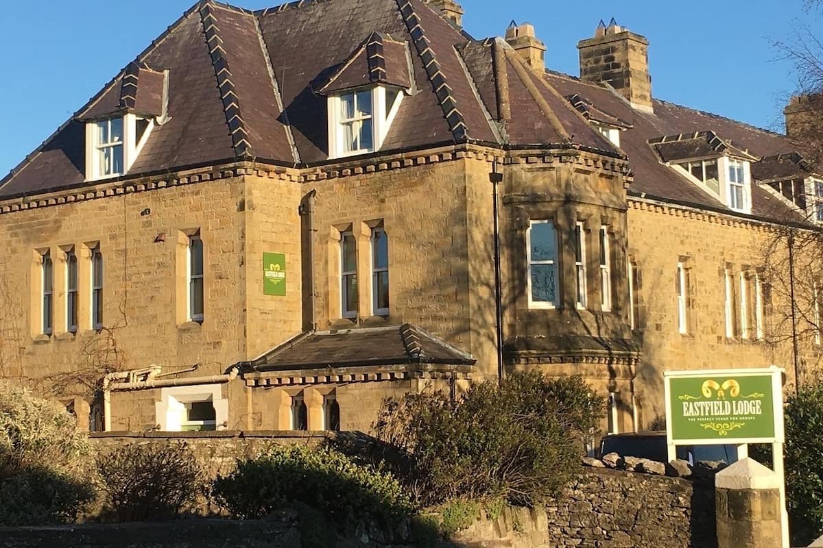A historic building with a stone facade, multiple windows, and a green sign indicating it is Eastfield Lodge.