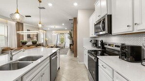 A modern kitchen with white cabinetry, stainless steel appliances, and pendant lighting. - EV_15883 - 6BR / 5BA Luxury Villa w/ Private Pool, Theater, Themed Kids' Room (Clermont)