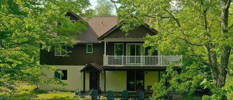 A two-story house with a balcony, surrounded by lush greenery.