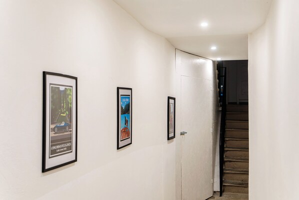 A hallway with framed pictures on the wall and a staircase leading to another room. - Casa Batèl Suites & Apartments (Como)