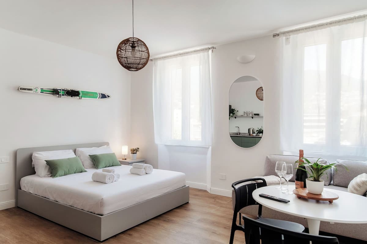 A modern bedroom with a bed, bedside table, and a dining area with a table and chairs.