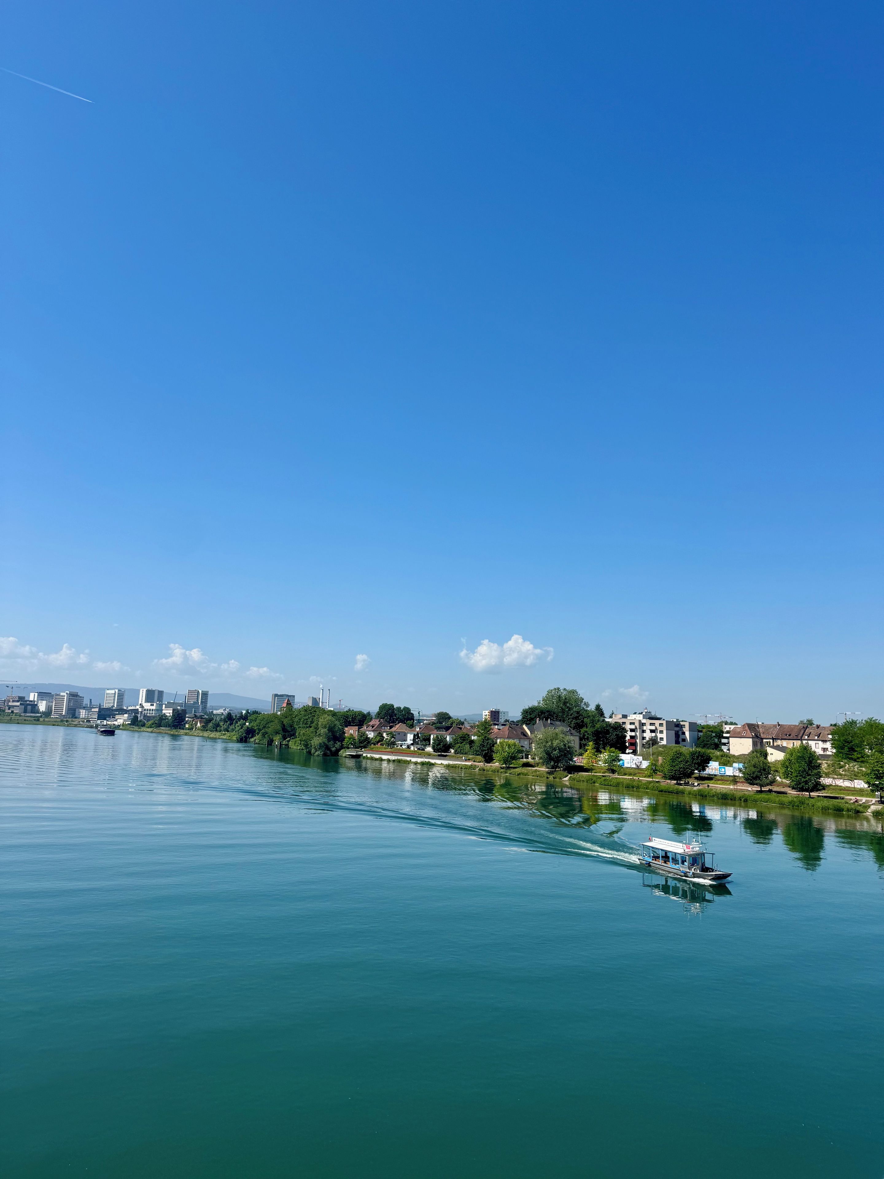 A river with a boat, buildings along the riverbank, and a clear sky.