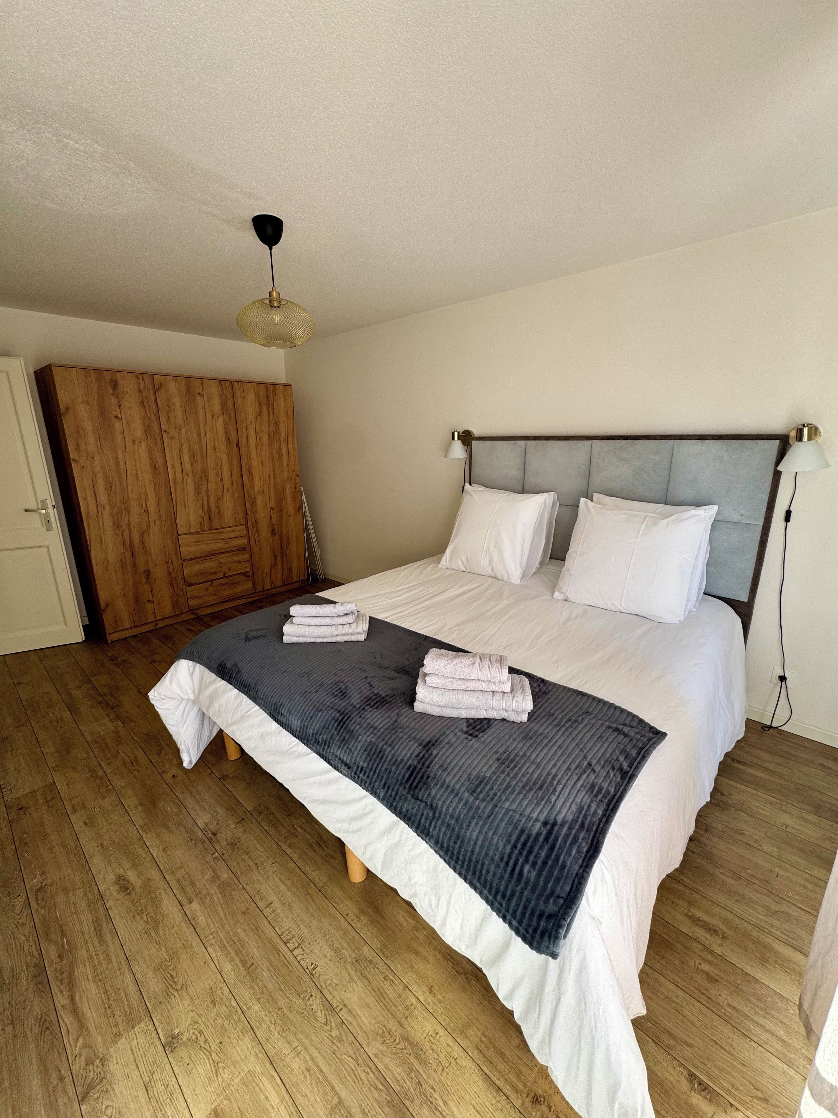 Une chambre à coucher avec un lit, une armoire en bois et un ventilateur de plafond.
