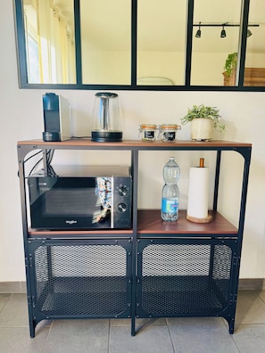 A kitchenette with a microwave, kettle, and storage jars.