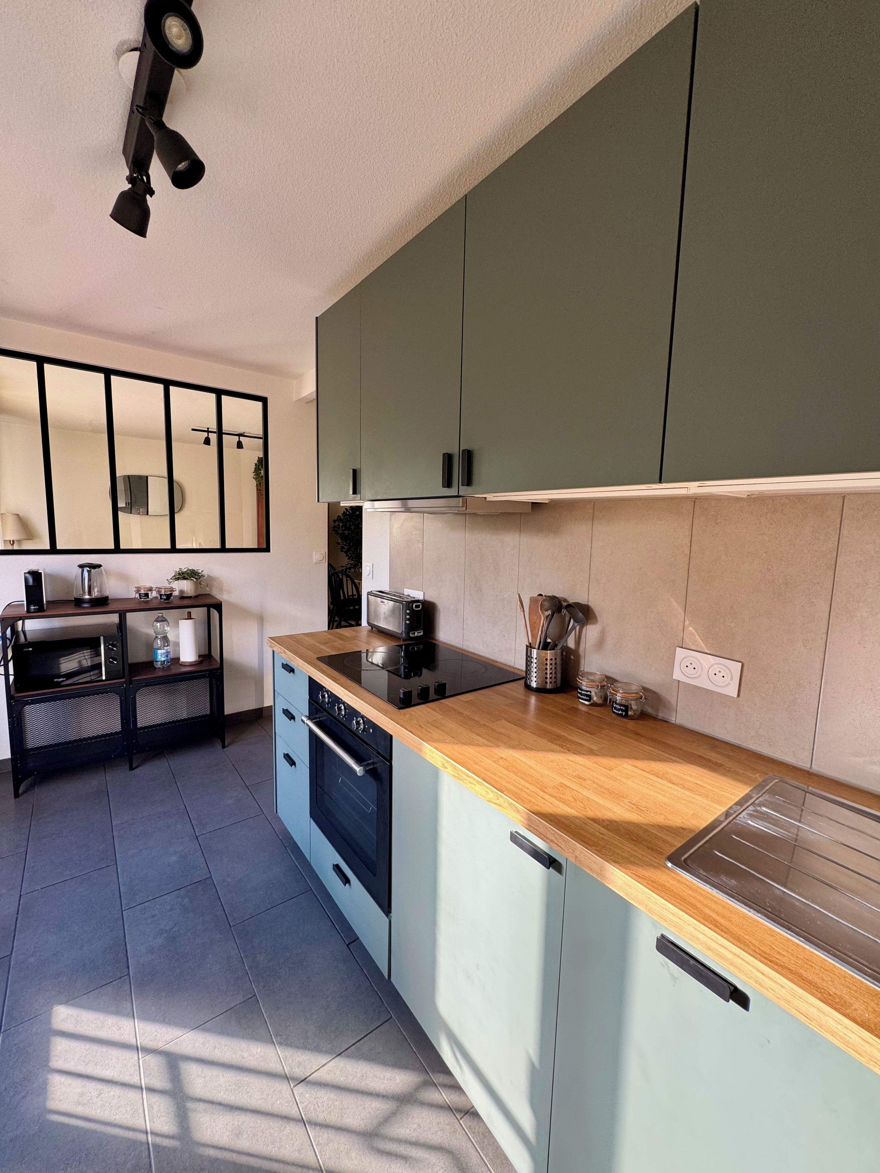 A modern kitchen with a wooden countertop, built-in oven, and a large green cabinet.