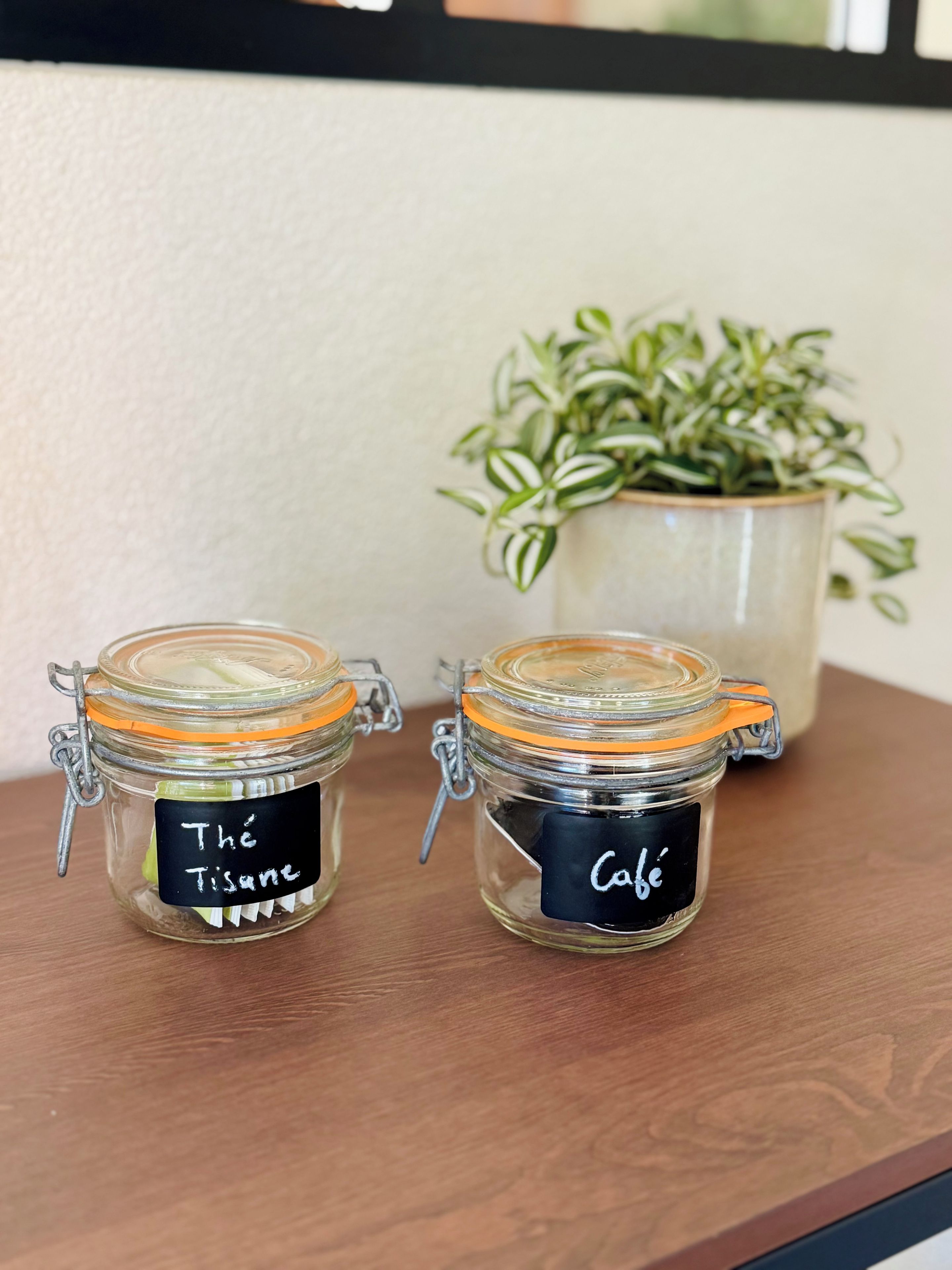 Two glass jars with metal clasps and black labels on a wooden surface.