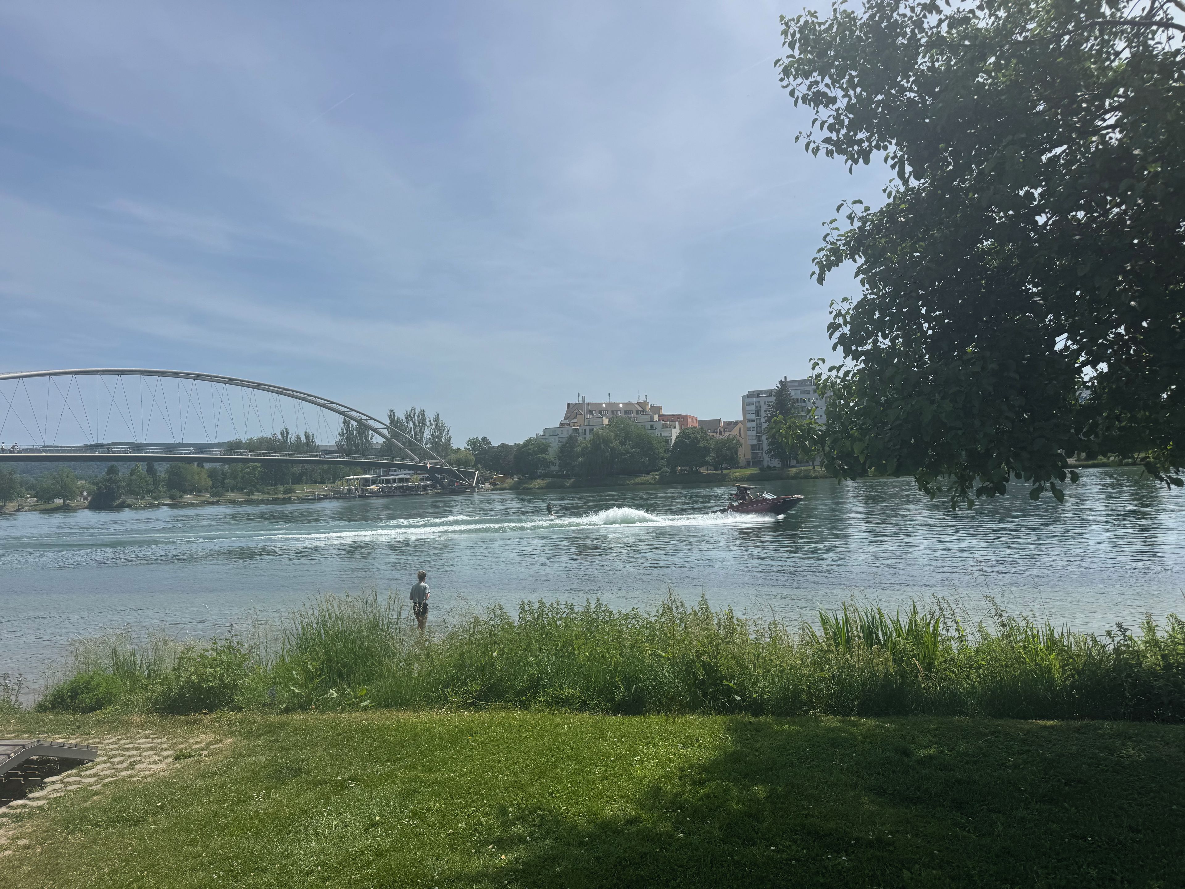 A river with a bridge, a boat, and a grassy bank.