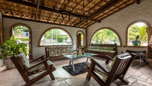 Un patio cubierto con paredes de ladrillo, ventanas arqueadas y mobiliario de madera.