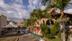Un patio con piscina, palmeras y un edificio de ladrillo con arcos.