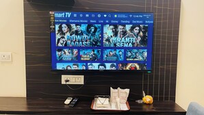 Ein Flachbildfernseher an einer dunklen Wand zeigt eine Streaming-Oberfläche mit Filmangeboten.