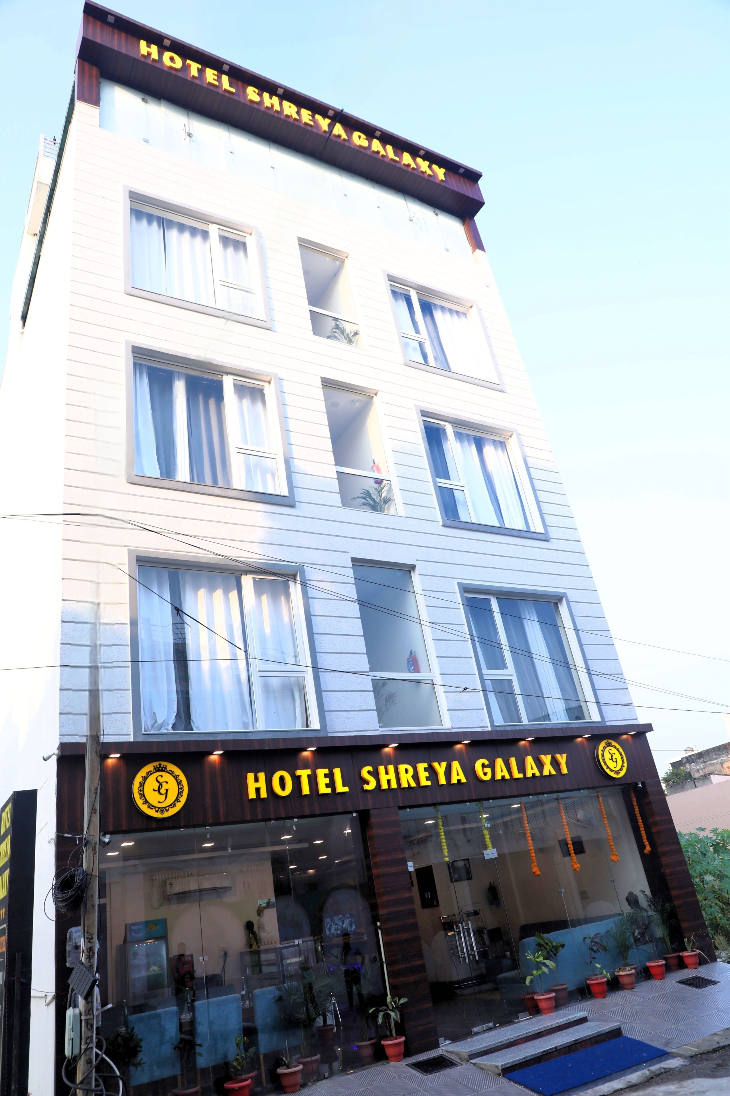 Un edificio de varios pisos con un letrero que dice 'Hotel Shreya Galaxy'.