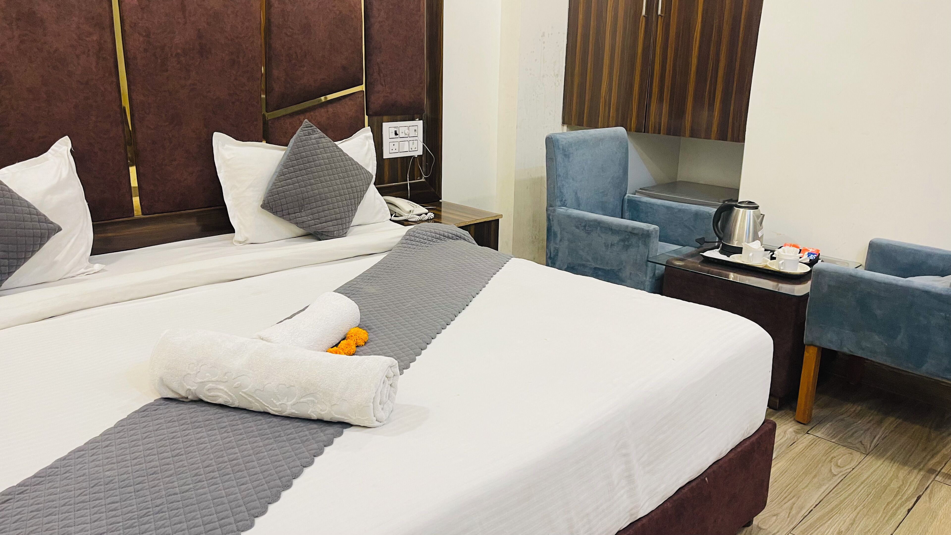 Een hotelkamer met een bed, een bureau met telefoon, een stoel en een koffiezetapparaat.