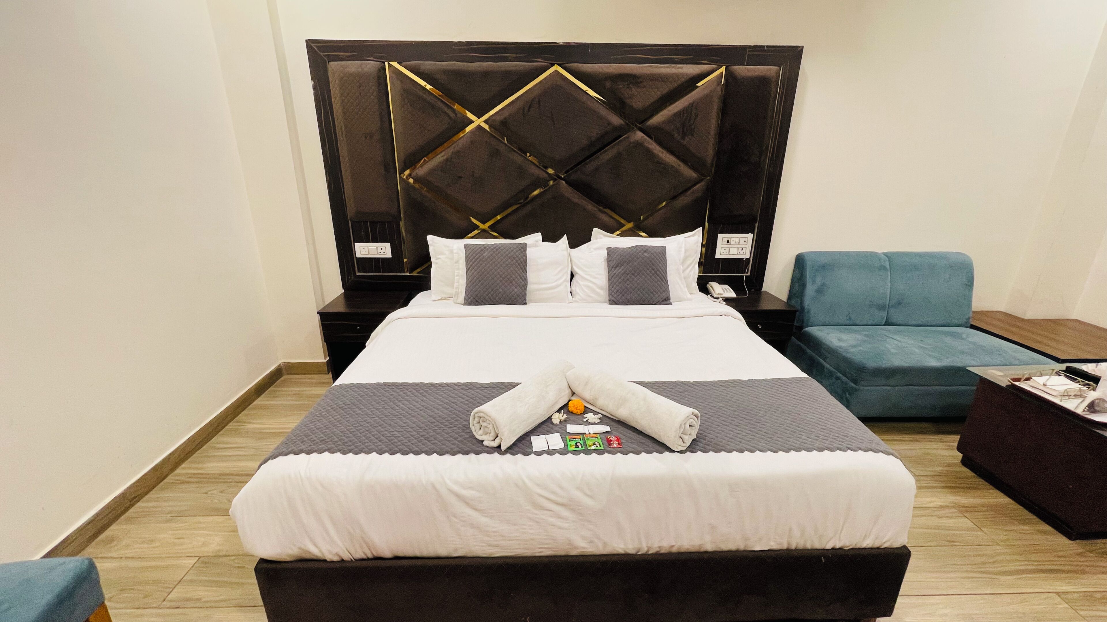 A hotel room with a large bed, a blue armchair, a small table, and a nightstand.