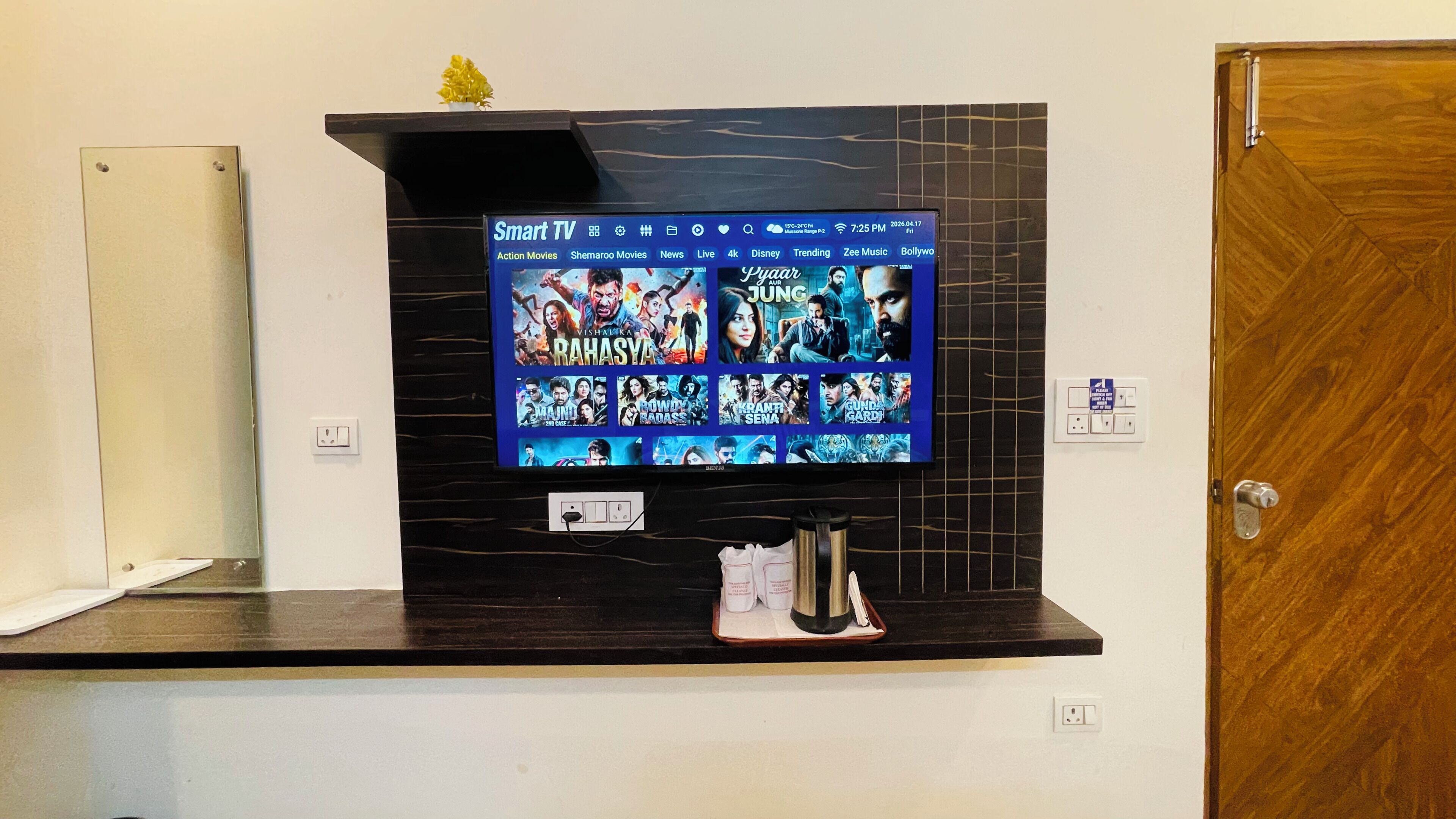Un televisor de pantalla plana montado en una pared oscura, con un panel de control debajo.
