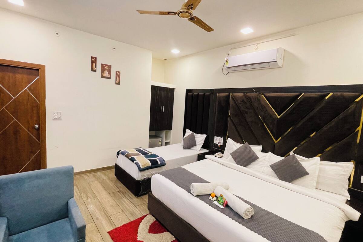 Habitación de hotel con cama, una silla, armario, aire acondicionado y ventilador de techo.
