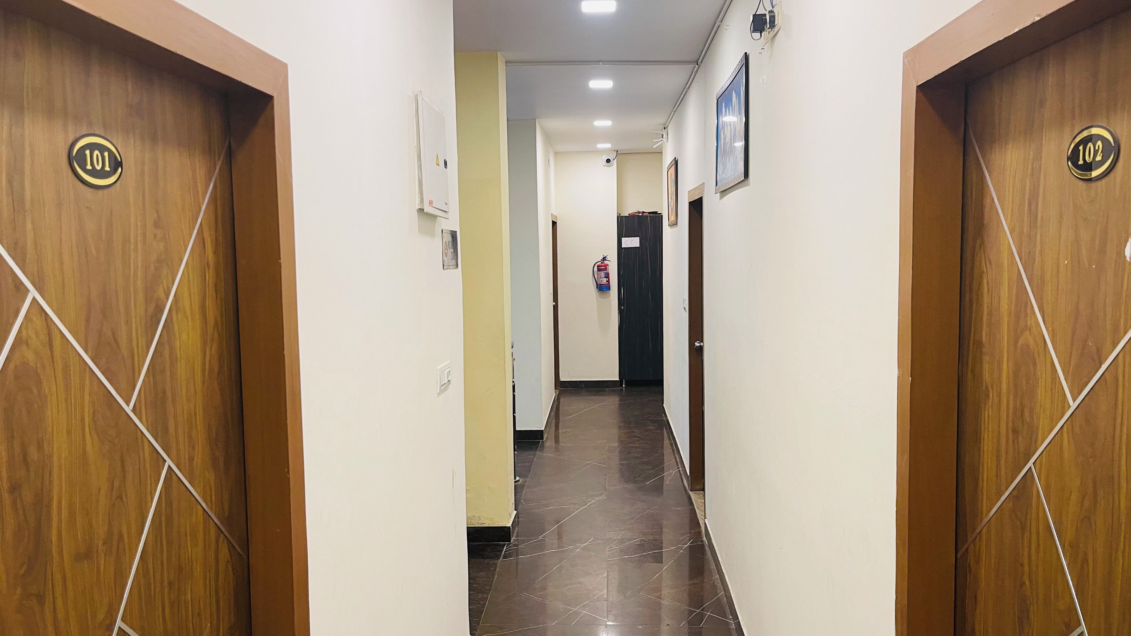 A hallway with wooden doors marked 101 and 102, a fire extinguisher, and a ceiling-mounted light fixture.