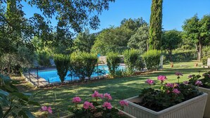 A pool surrounded by lush greenery and flowering plants. - Spacious, bright gîte, ideal for large families or groups of friends. (Ruoms)